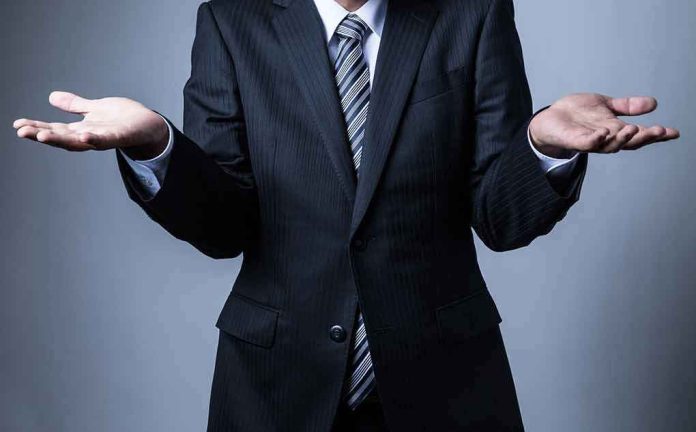 shutterstock_499983775 Businessperson in suit shrugging with open hands