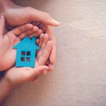Inflation DIPS — Anomaly or TREND? Hands holding a blue house cutout