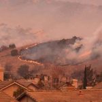 Fires SPREAD, Evacuations SURGE, Systems BUCKLE Wildfire burns on hillside near suburban homes