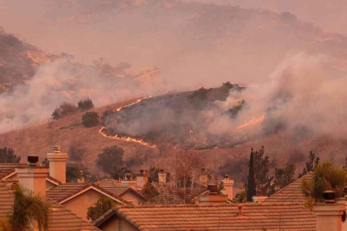 Wildfire burns on hillside near suburban homes