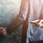 Beloved Star Betrayed — Trusted Family Member’s DESPICABLE Demand businessperson shakes hands while crossing fingers behind back