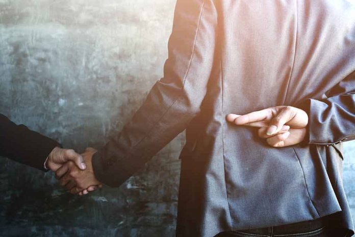shutterstock_1007250361-1 businessperson shakes hands while crossing fingers behind back