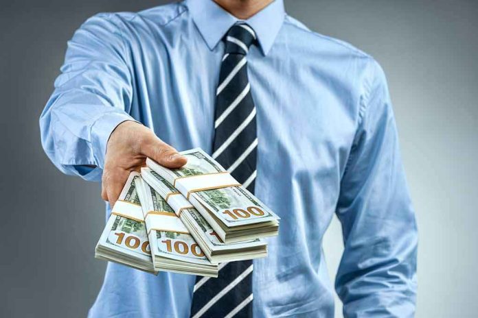 shutterstock_1008204853 Person in business attire offering bundles of US dollar bills