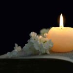 Candle on an open book with white flowers