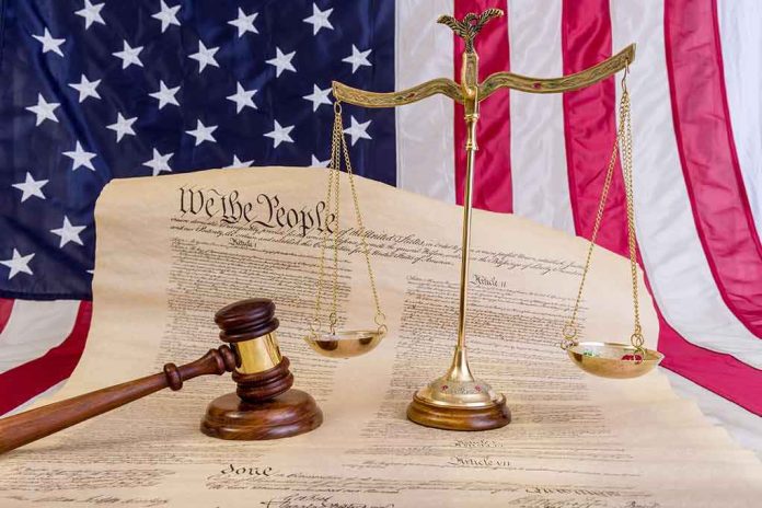 shutterstock_1089834518 Scales of justice and gavel on the U.S. Constitution with American flag backdrop