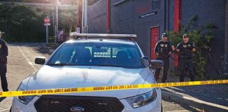Aaron Guiel near police car behind yellow caution tape