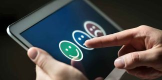 Hands using a tablet to select a happy face rating