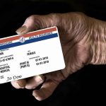 Elderly hand holding a health insurance card