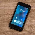 Thief Never Cracked A Password. So WHO Opened The Door? Smartphone showing an incoming scam call on a wooden surface