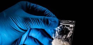 It’s Stronger Than FENTANYL — And The Test Strips Can’t See It Gloved hand holding a small plastic bag of white powder