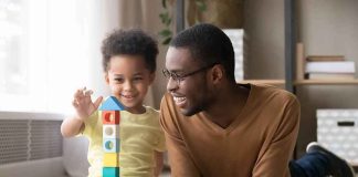 Trump UPENDS Child Care — What Changes Now? Child and adult building a tall tower with colorful wooden blocks