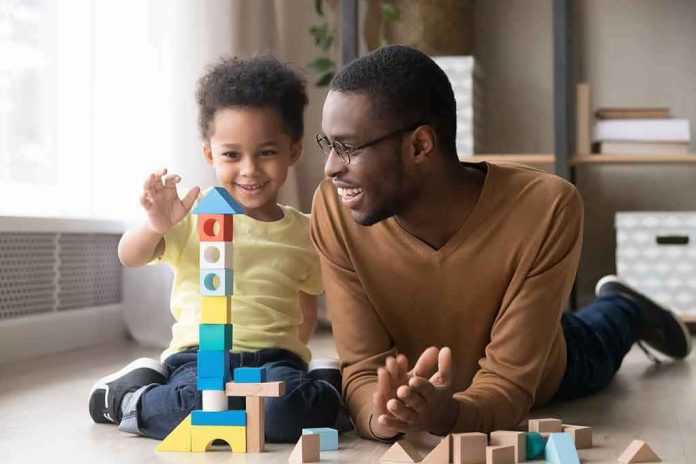 shutterstock_1319345771 Child and adult building a tall tower with colorful wooden blocks