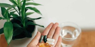 WARNING: Faster DEMENTIA Linked To Popular Joint Pill Hand holding assorted pills next to a plant and a glass of water
