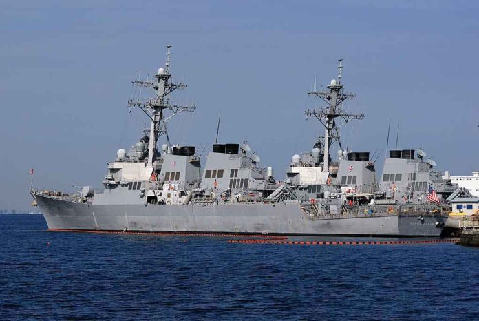 shutterstock_1626607414 Three gray naval destroyers docked side by side at a pier