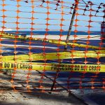 Horror MAULING Shuts POPULAR Beach Orange safety net and yellow police tape blocking a beach access