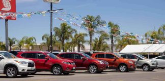 Row of new cars on a dealership lot under pennant flags