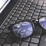 Smart Glasses Filmed People In Bathrooms — Look Who Got The TAPE Black eyeglasses resting on a laptop keyboard
