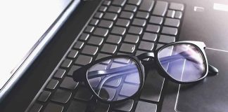 Black eyeglasses resting on a laptop keyboard