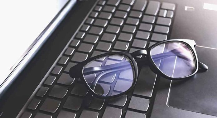 shutterstock_1748103815 Black eyeglasses resting on a laptop keyboard