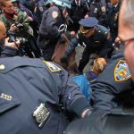 Tourist Hub CHAOS — Blade, Bullets, Panic Police officers detain a person during a crowded street protest