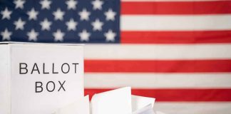 Ballot box with papers in front of an American flag