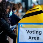 UNEXPECTED Power Shift Brewing In New Hampshire voter wearing a mask using a yellow ballot box