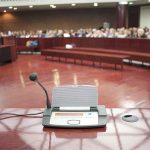 Fauci FINALLY Gets HIS COMEUPPANCE! Conference microphone on a podium in a courtroom