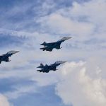 Three fighter jets flying in formation against a cloudy sky