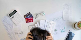 Check Your Next Card Statement — The Fed Just Made It WORSE Person holding head over bills and credit cards on desk
