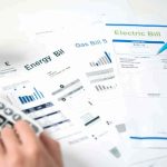Look At Your Electric Bill — Somebody Else’s Power Is ON IT Hands reviewing utility bills with calculator and pen