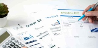 Look At Your Electric Bill — Somebody Else’s Power Is ON IT Hands reviewing utility bills with calculator and pen