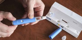 Smuggled FAKE Ozempic Hit U.S. Drug Suppliers — The Sellers KNEW It Hands taking the cap off a blue injection pen, with its package on the table