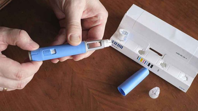 shutterstock_2151232809 Hands taking the cap off a blue injection pen, with its package on the table