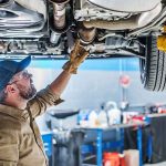 Mechanic inspecting underside of a car on a lift