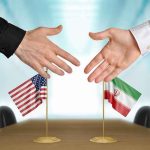 Hezbollah Becomes The DEALBREAKER Two hands reaching to shake above US and Iran flags on a conference table