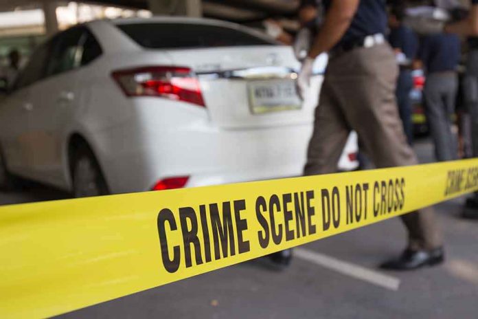 shutterstock_351048443 Yellow crime scene tape in front of a white car with investigators nearby