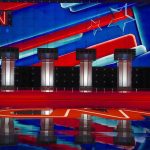 Debate stage with four podiums and colorful star backdrop
