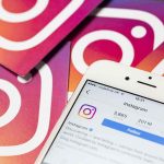 Smartphone showing Instagram profile on colorful logo cards