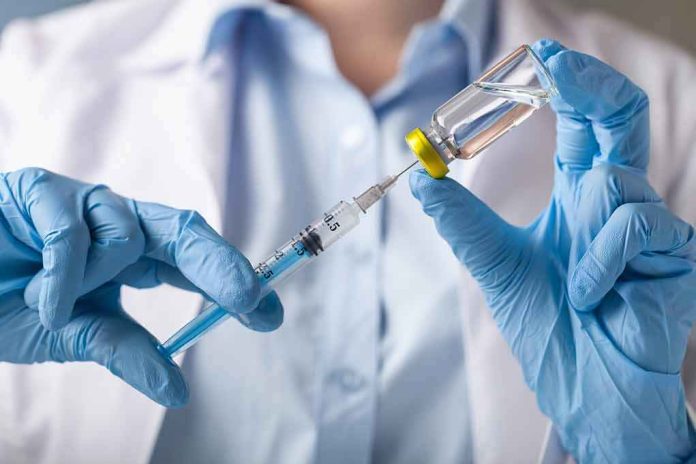 Gloved hands drawing liquid from a vial with a syringe