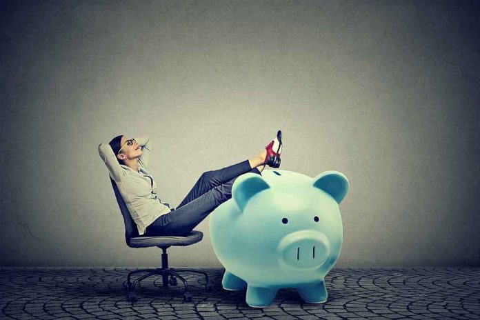 shutterstock_685872724 Woman relaxing in chair with feet on giant blue piggy bank