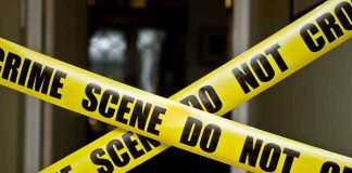Mom FOUND Dead — Son CHARGED For What He COLLECTED Yellow crime scene tape crossing a doorway