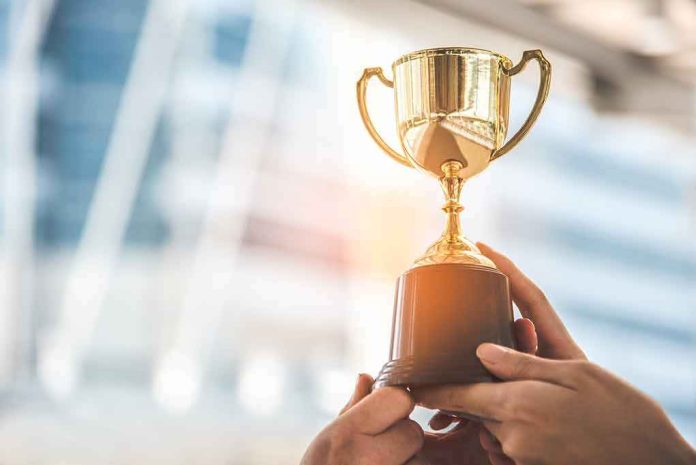shutterstock_1113947324-1 Hands holding a golden trophy cup
