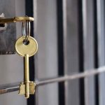 Golden key hanging from a lock on a metal jail cell door