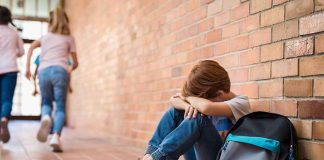 Mom Sent Her ‘Troubled’ Boy AWAY — Then Came His Test RESULTS boy sitting against brick wall with head on arms and backpack