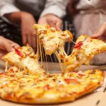 Food Giant AXES Iconic Pizza — Your FAVORITE Could Be NEXT Hands pulling cheesy pizza slices from a box