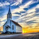 White country church with steeple at sunset