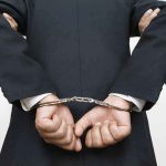 Councilman ARRESTED At Homecoming For What He Brought person in a suit with hands cuffed behind back