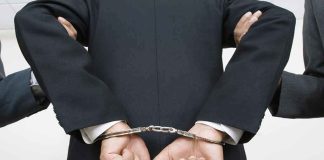 Councilman ARRESTED At Homecoming For What He Brought person in a suit with hands cuffed behind back