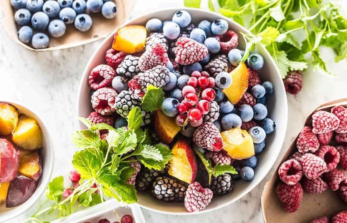 shutterstock_1443256970 Bowl of mixed frozen berries and peach slices