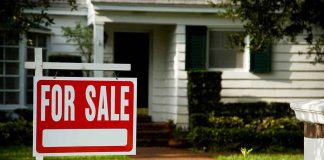 For sale sign in front of a suburban house